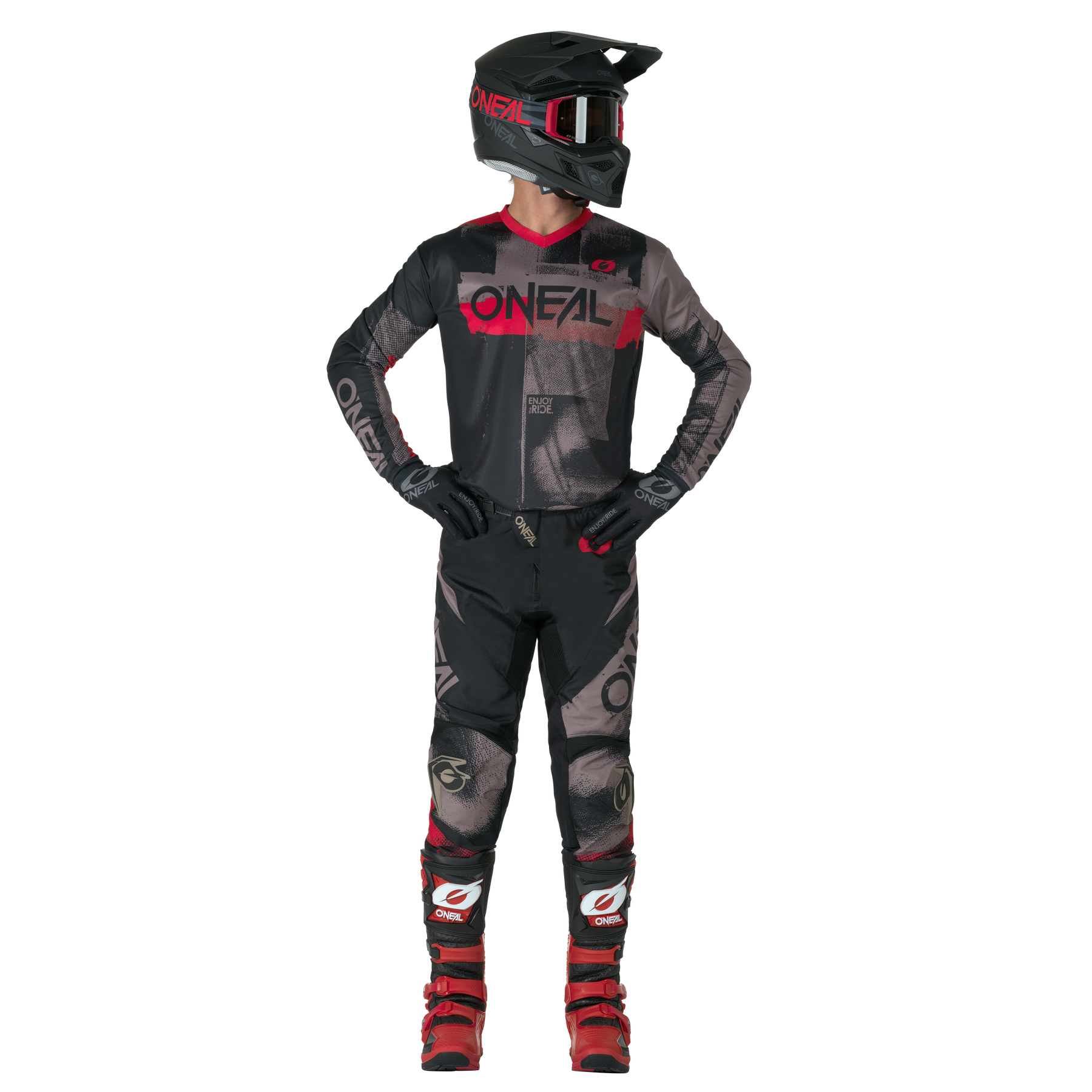 Eine Person in voller Motocross-Ausrüstung - schwarzes und rotes O'NEAL-Trikot, Handschuhe, rote Stiefel und O'NEAL ELEMENT Pants ROLLER - steht da und schaut zur Seite.