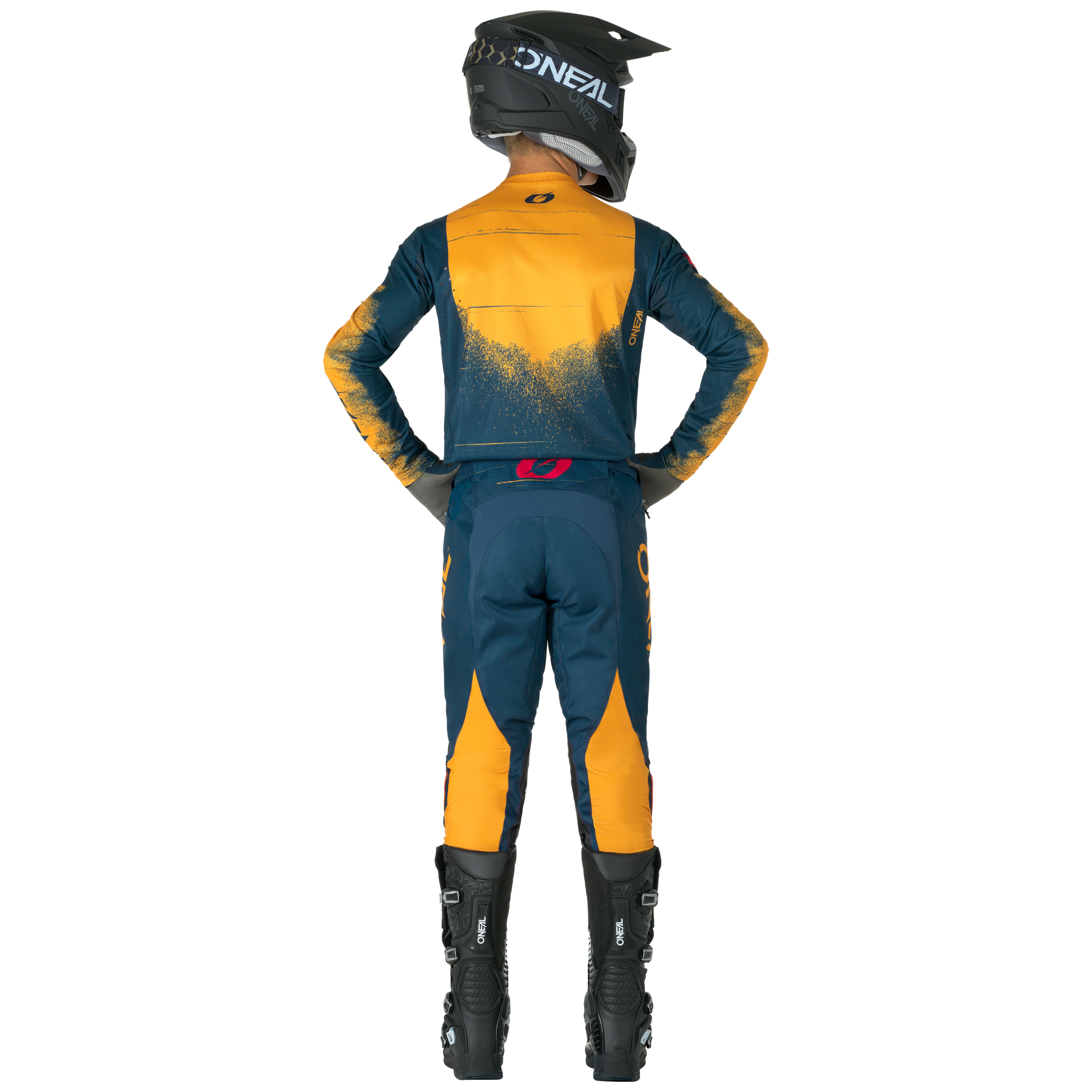 Eine Person, die O'NEAL HARDWEAR Pants SWIPE und einen passenden O'NEAL-Motocross-Anzug, einen Helm und schwarze Stiefel trägt, steht mit den Händen in den Hüften, von der Kamera abgewandt.