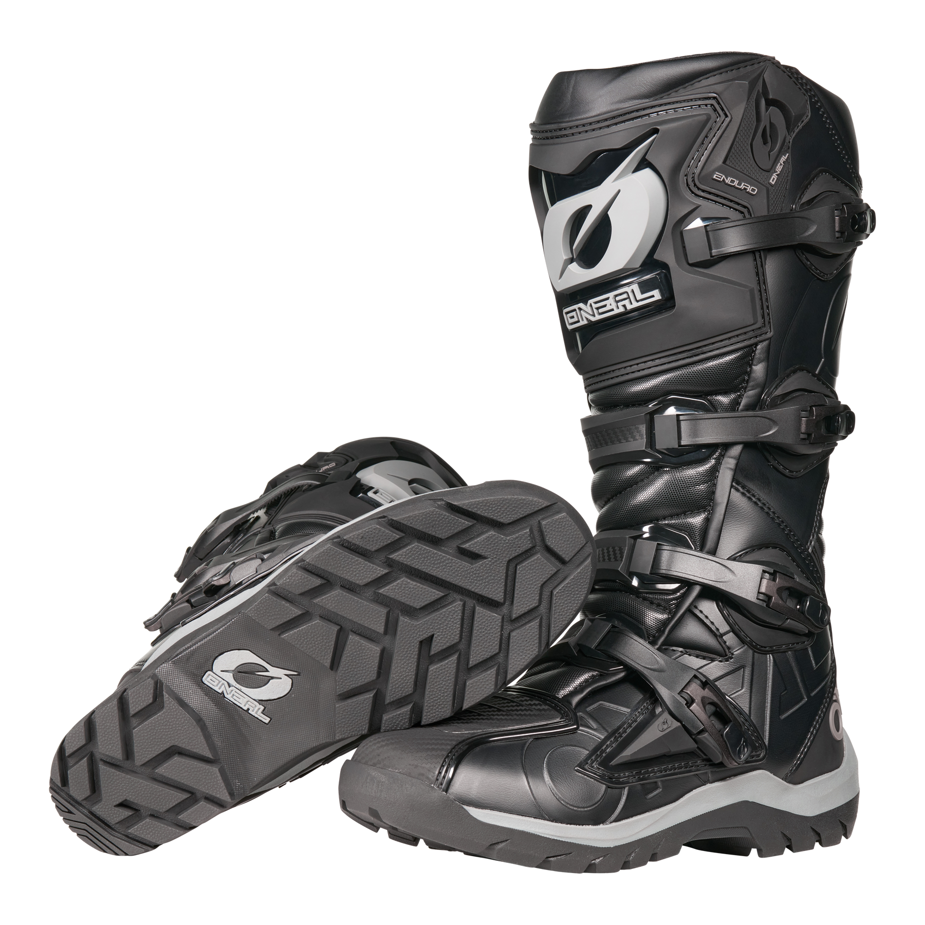 Der O'NEAL RMX Adventure Boot in Schwarz und Grau verfügt über robuste Sohlen, Schutzschnallen und verstärkte Schienbeinschützer. Ein Stiefel steht aufrecht, während der andere seitlich liegt, um das Profil zu betonen - ideal für Motorsportler.