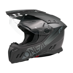 Ein Schwarz/Weiß O'NEAL SIERRA RS Helm SOLID mit klarem Visier, aerodynamischen Belüftungsöffnungen, Quin Smart Safety Sensor und fetten seitlichen Schriftzügen wird vor einem schlichten schwarzen Hintergrund dargestellt.