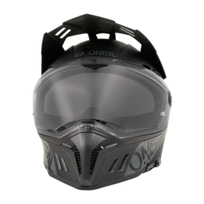 Ein schwarzer O'NEAL SIERRA RS Helm SOLID Motorradhelm mit klarem Visier, kantigen Belüftungsöffnungen und matten Grafiken wird von vorne auf einem transparenten Hintergrund gezeigt. Kompatibel mit dem Quin Smart Safety Sensor für zusätzlichen Schutz.