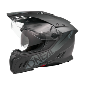 Ein mattschwarzer O'NEAL SIERRA RS Helm SOLID Motorradhelm mit klarem Visier, aerodynamischen Belüftungsöffnungen und stabilem Kinnschutz, dargestellt im Seitenprofil auf transparentem Hintergrund. Kompatibel mit Quin Smart Safety Sensor.