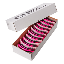 Öffne die weiße Box mit der O'NEAL B-ZERO Goggle (10 Stück). Darin findest du pink/klare Schutzbrillen, ordentlich angeordnet und durch Schutzmaterial getrennt. Der Deckel ist teilweise geöffnet und zeigt stolz das O'NEAL-Logo.