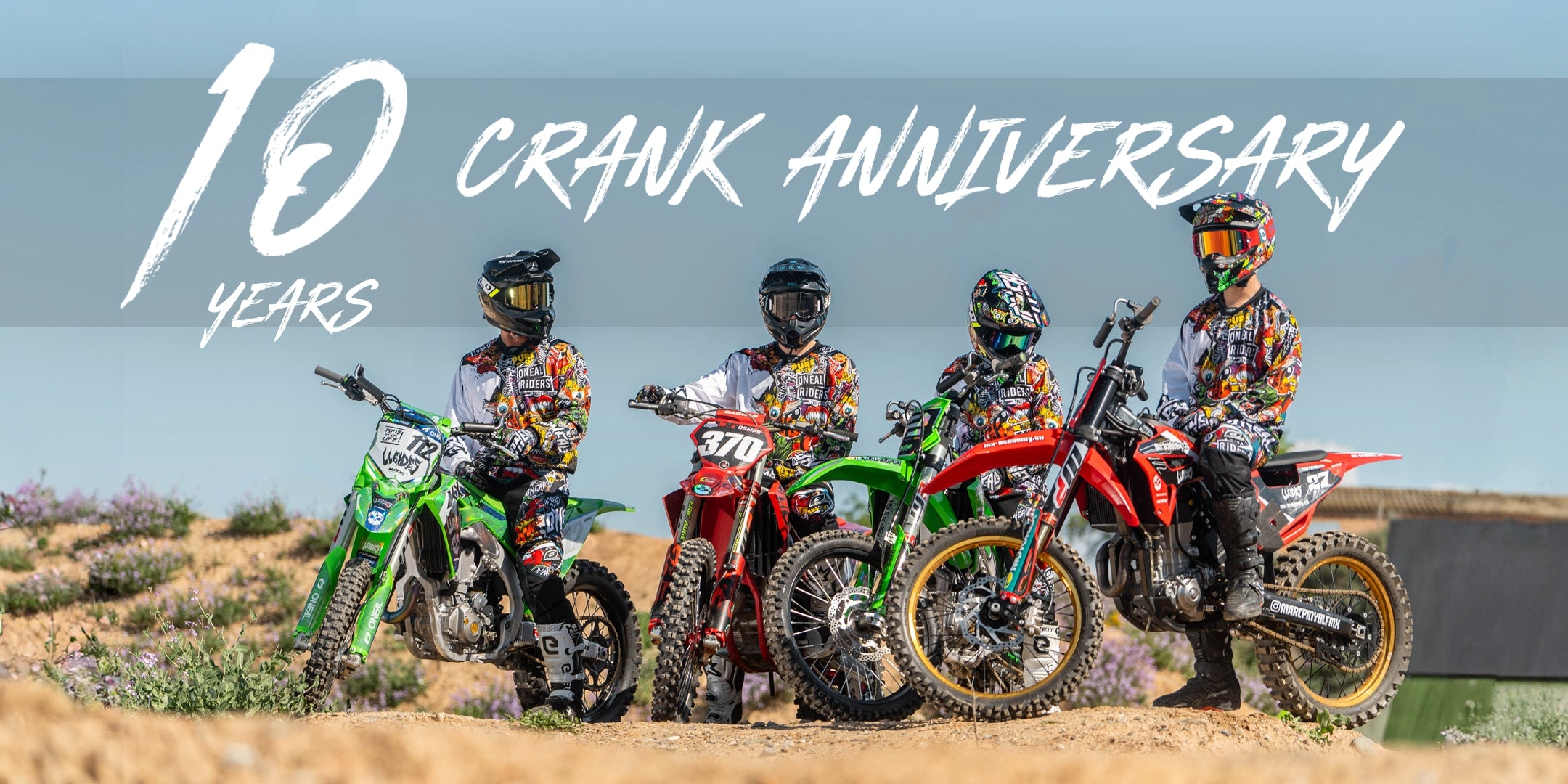 Vier Motocross-Fahrer in farbenfroher Ausrüstung sitzen auf ihren Dirtbikes auf einer unbefestigten Strecke unter blauem Himmel. Oben im Bild steht in großer Schrift „10 Jahre Crank-Jubiläum“.