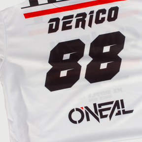 Das Bild zeigt die Rückseite eines O'NEAL Custom Jersey Kinder SQUADRON in Weiß mit schwarzen und roten Akzenten. Der Name „DERICO“ ist in fetten schwarzen Buchstaben über den oberen Rücken gedruckt, und darunter ist deutlich die Nummer „88“ zu sehen. Dieses im Sublimationsverfahren hergestellte individuelle Jersey trägt unten das Markenlogo „O'NEAL“.