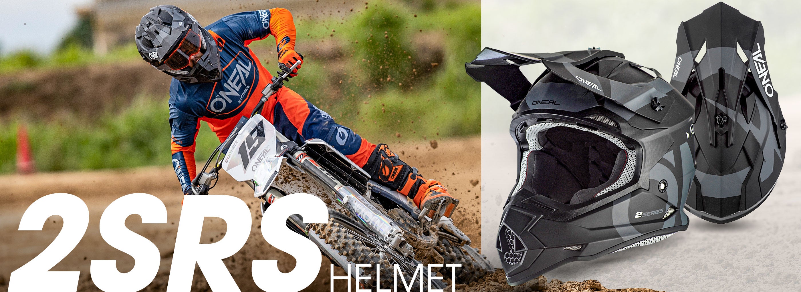 Ein Motocrossfahrer in orange-blauer Ausrüstung fährt ein Dirtbike auf einer Rennstrecke. Neben dem Fahrer sind zwei Ansichten eines schwarzen VEMAR 2SRS-Helms mit Visier zu sehen. Unten im Bild steht in großem, überlappendem Text „2SRS-HELM“.