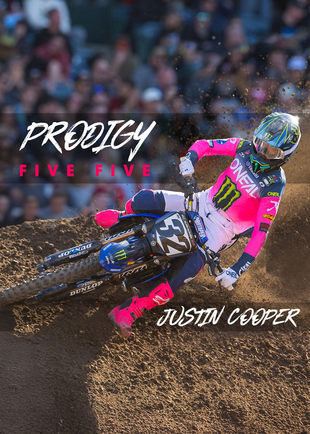 Ein Motocross-Fahrer in leuchtendem Pink und Blau lehnt sich während eines Rennens in eine Dirt-Kurve. Das Motorrad hat die Nummer 32. Der Overlay-Text lautet „PRODIGY FIVE FIVE“ und „JUSTIN COOPER“.